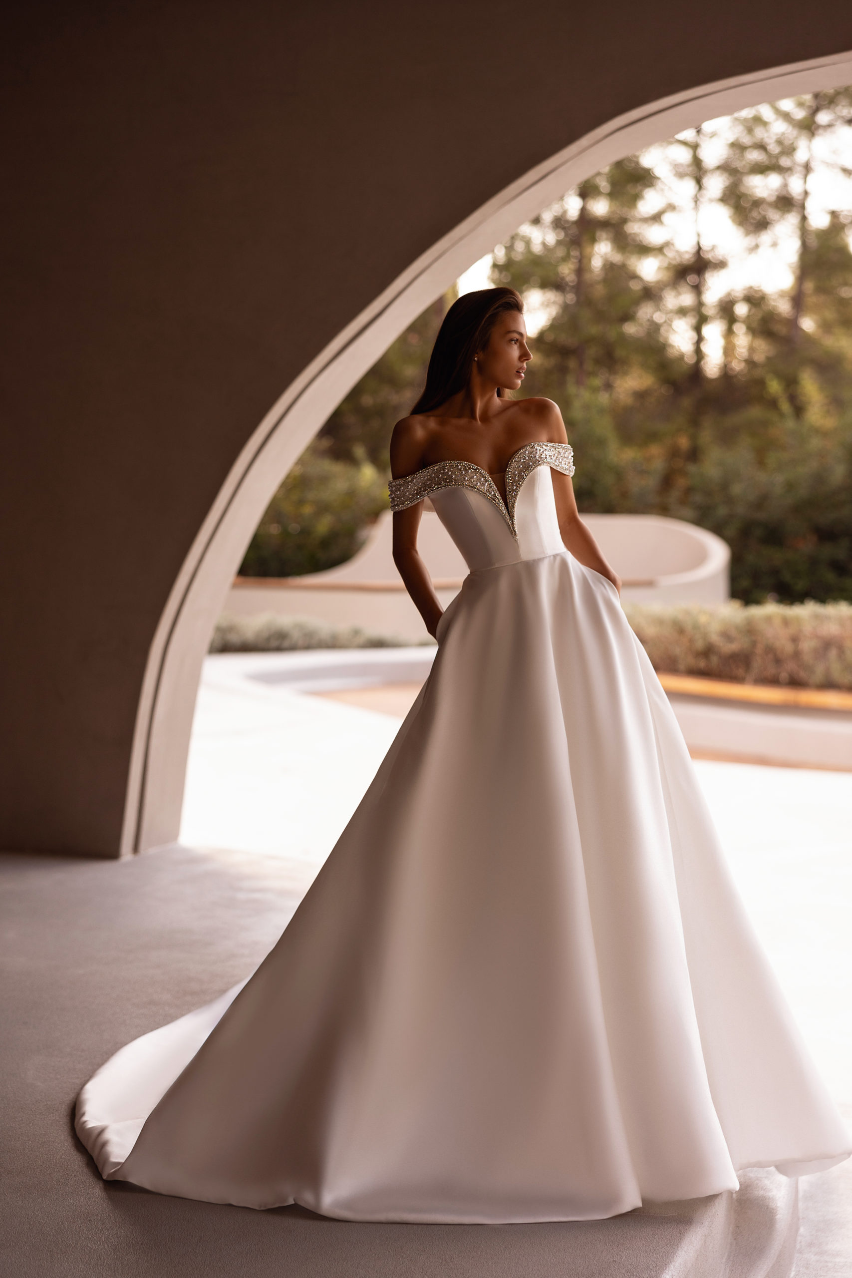 robe de mariée Demetrios 1517, bustier décolleté avec épaules dénudées et perles, jupe volumineuse en satin, photo en décor moderne