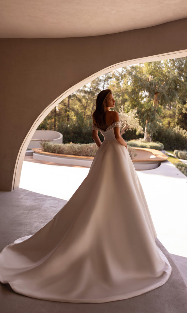 robe de mariée Demetrios 1517, bustier décolleté avec épaules dénudées et perles, jupe volumineuse en satin, photo en décor moderne