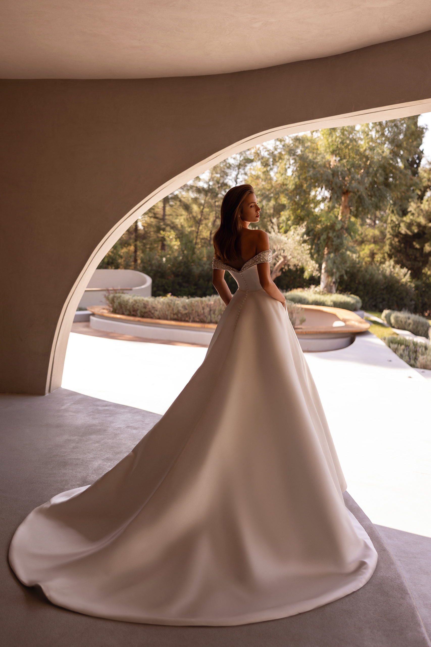 robe de mariée Demetrios 1517, bustier décolleté avec épaules dénudées et perles, jupe volumineuse en satin, photo en décor moderne