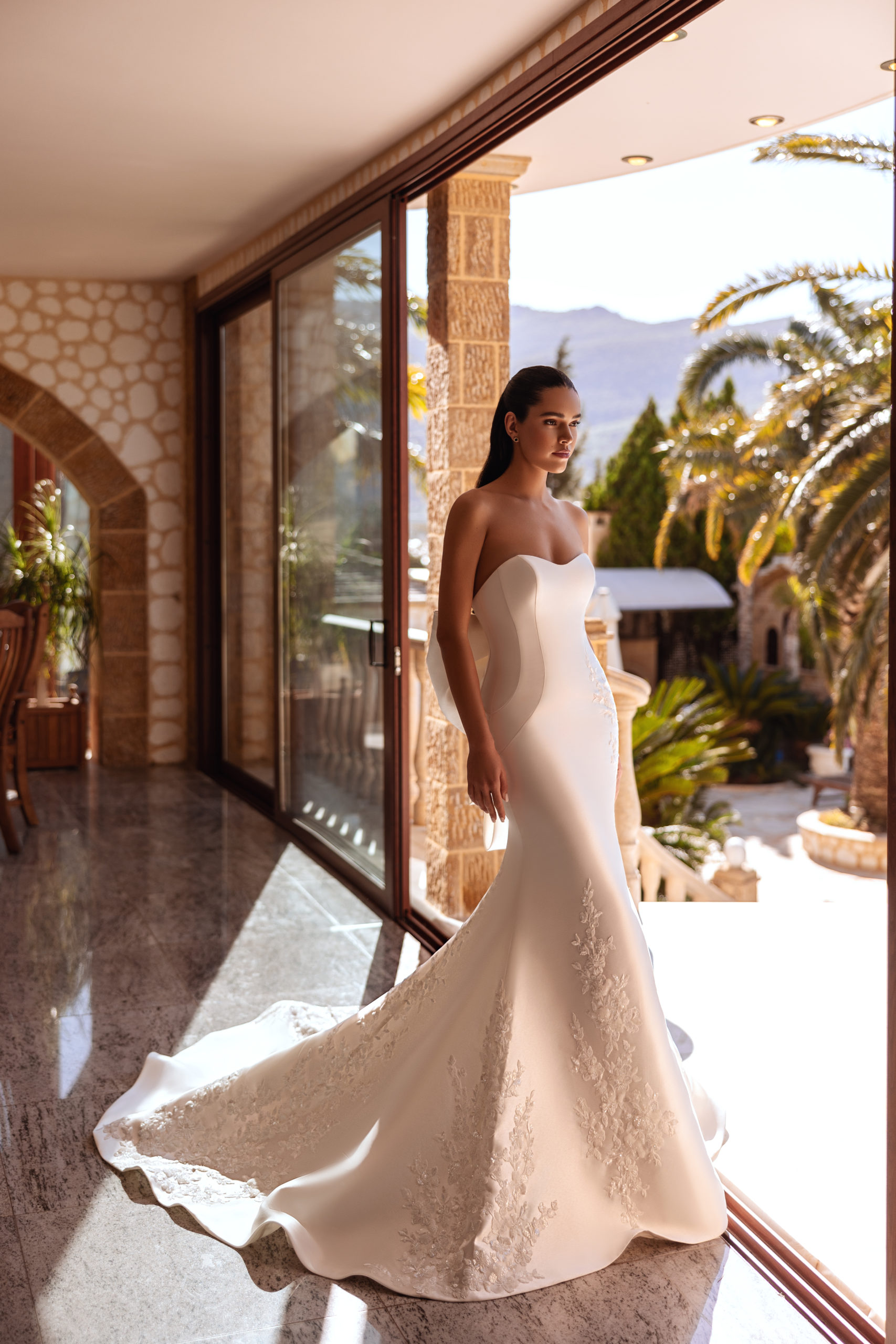 robe de mariée Cosmobella 8257 en coupe sirène, bustier cœur et broderies florales, photo en terrasse avec palmiers