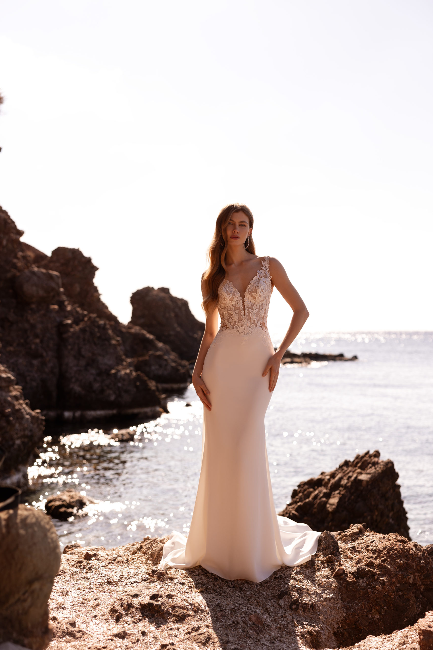robe de mariée Demetrios DR420 coupe sirène avec bustier en dentelle transparente, dos échancré et jupe fluide au bord de mer