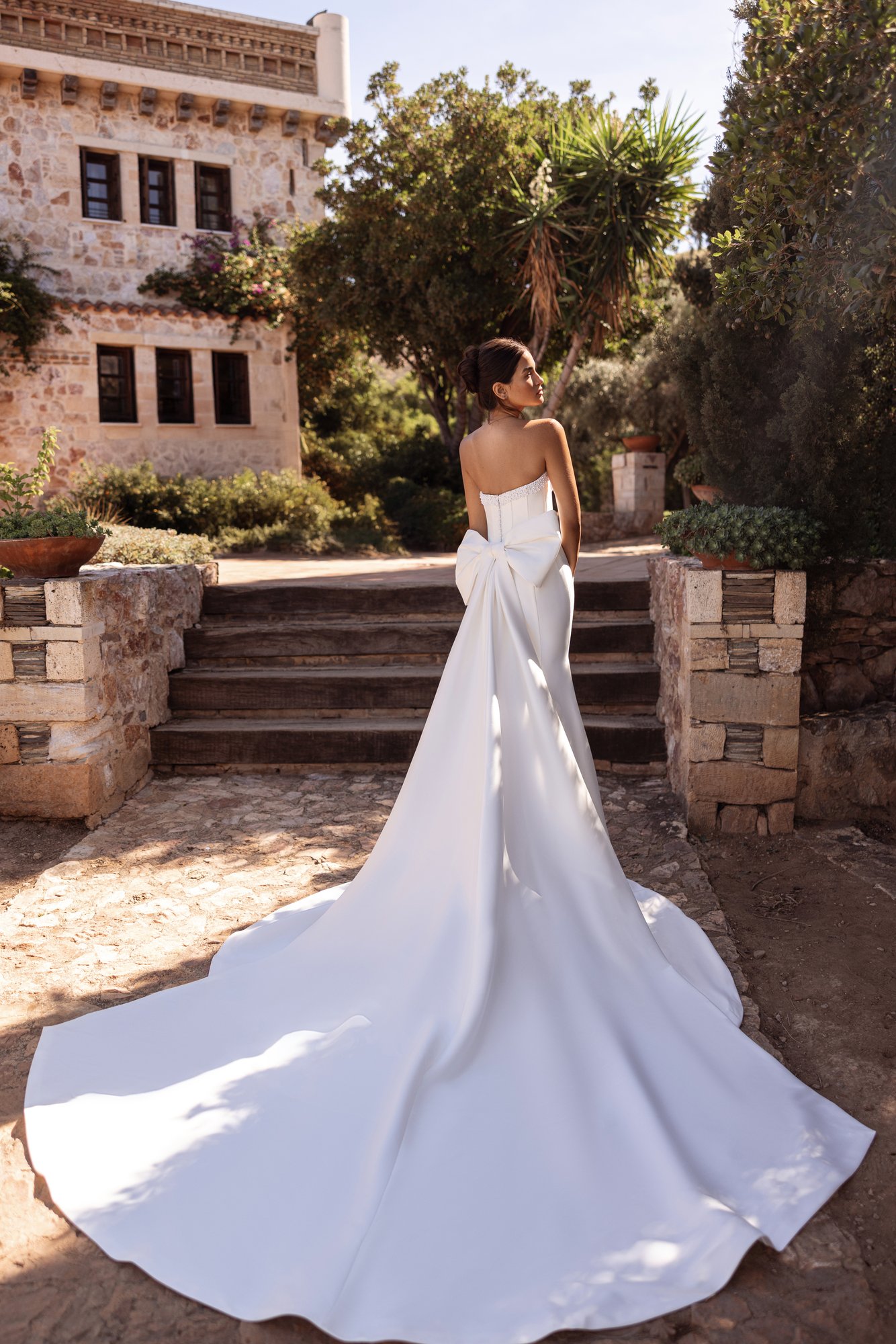 Robe de mariée Cosmobella 8295 vue de dos avec sa traîne évasée.