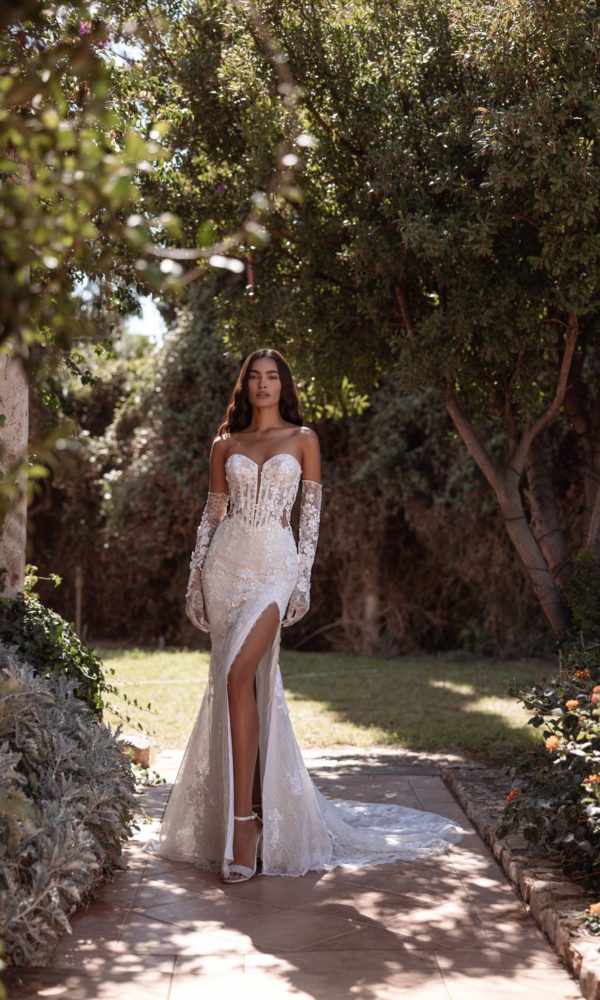 Robe de mariée Cosmobella 8297 à motifs floraux et jupe fendue, présentée avec de longs gants.